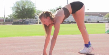 Athletic blonde girl is doing splits on the track