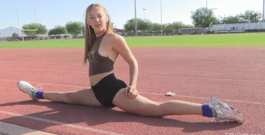 Athletic blonde girl is doing splits on the track